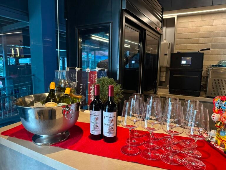 Wine bottles and glasses on a red cloth, with a silver ice bucket