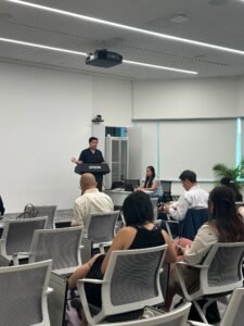 A speaker presents at a podium in a conference room