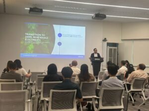 Speaker presents on Epson's transition to 100% renewable electricity to an attentive audience in a modern conference room