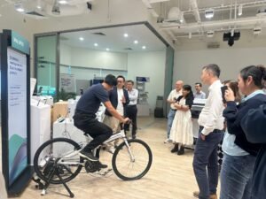 Man pedals stationary bike in office demo, showcasing Epson's compact printers